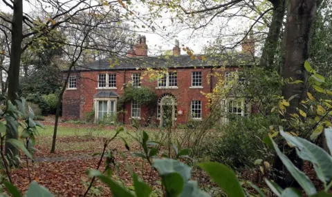 Red House Museum building with leaves and woodland around them 