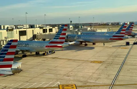 Multiple American airlines planes sit parked at a gate