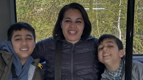 Shahida hugs her sons for a family photo on a bus.