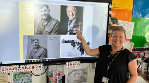 Miss Jackson stands in front of a screen showing pictures of Mervyn when he enlisted and when he turned 100.