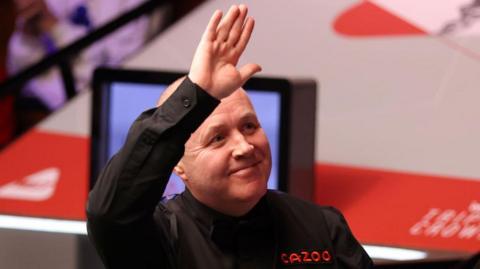 John Higgins waves to the crowd at the Crucible