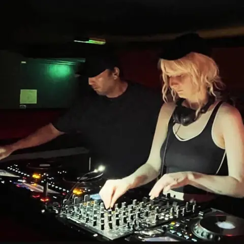 Jobson family A man in a black t-shirt DJs beside a young woman with blonde hair in a black vest top.