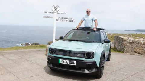 TimbuktuContent.com/EaseeSunRun A blue SUV-style car is parked next to a Land's End signpost, which has several fingers pointing in the direction of different places, along with the distances. A man is standing in the car, with his torso out of the car through the soft roof. Behind him is the sea.