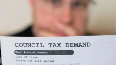Getty Images Man looking at a council tax bill