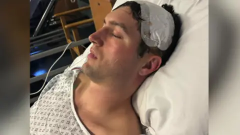 Jasper Dix A man lying in a hospital bed with his eyes closed.