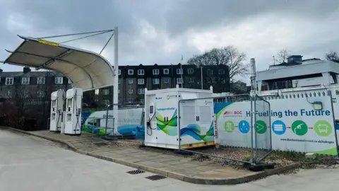 A hydrogen fuelling station, with rows of flats in the background.