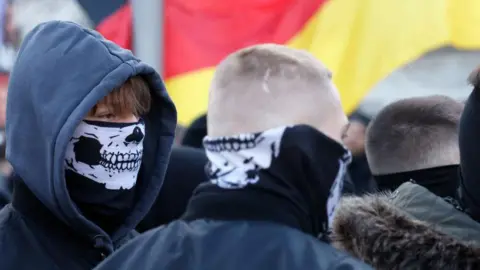 Young men hold flags of Germany as they attend a march of extreme right supporters on February 22, 2025 in Berlin, one day before general elections.
