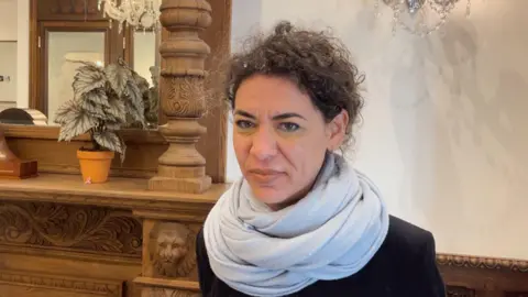 woman wearing scarf standing in front of mantlepiece 