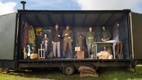 Alistair Corbett The mobile museum opens up on one side to exhibit a range of World War Two memorabilia. There are five war uniforms and two child sized models clothed.