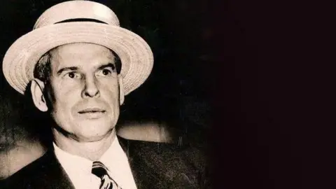 Getty Images Llewellyn Morris Humphreys - better known as Murray the Hump - is smartly dressed in collar and tie, he is wearing a cream colour hat with a black ribbon around it. He looks every inch a society gentleman