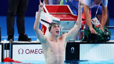 Getty Images Daniel Wiffen in the swimming pool with his arms raised after winning the Olympic gold 