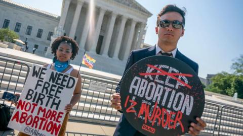 Two people protest against abortion in front of the Supreme Court building.