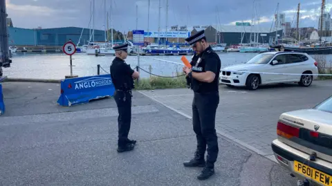 Two uniformed police officers stand at Ipswich Marina.