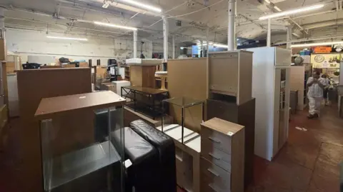 Donated cabinets, drawers and wardrobes are being stored in a large warehouse. 