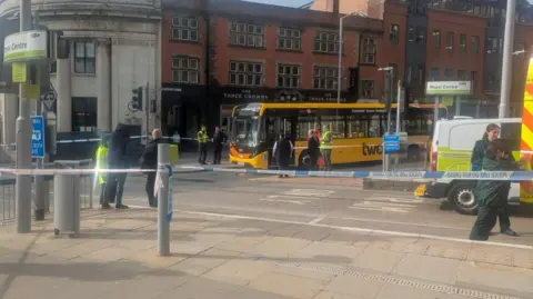 A tram stop is pictured with police cordon tape blocking the route