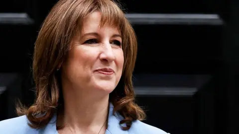 Rachel Reeves smiling in front of black Downing Street door