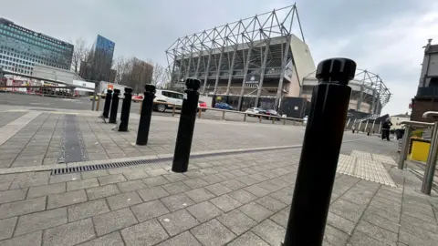 Strawberry Lane, overlooking St James' Park. It is a tall white building with Newcastle United's logo. 