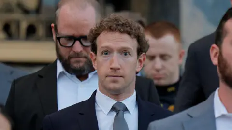 Mark Zuckerberg walking down the grey stone steps of a Los Angeles court house wearing a navy suit blazer, grey neck tie and white shirt. 