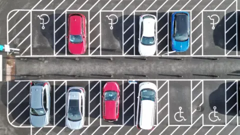 A Birds Eye view of cars being parked in a disabled car parking bay.