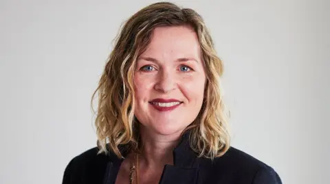 CIPD Headshot of Claire McCartney. She has blue eyes, wears red lipstick, and has shoulder-length blonde hair with brown roots