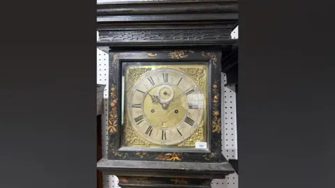 Chilcotts Auctioneers and Valuers A black and gold clock with a gold face. The picture is on a black background. 