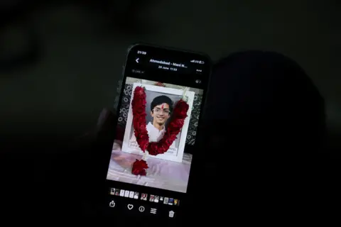 Reuters Prashant Patel, 45, shows a photo of his 17-year-old son Kahaan Patel, who took his own life ahead of the NEET exam retest, in Ahmedabad
