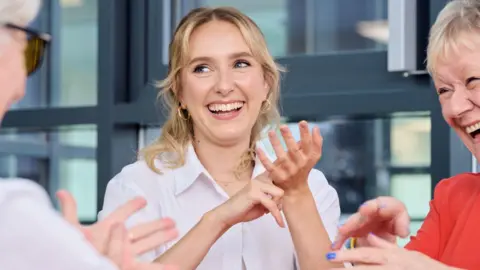 Rogan Productions Rose Ayling-Ellis smiles as she signs with her hands 