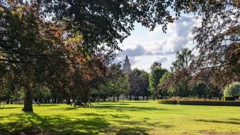 Local Democracy Reporting Service A picture of a lawn at the War Memorial Park lined with trees and with a war memorial in the background