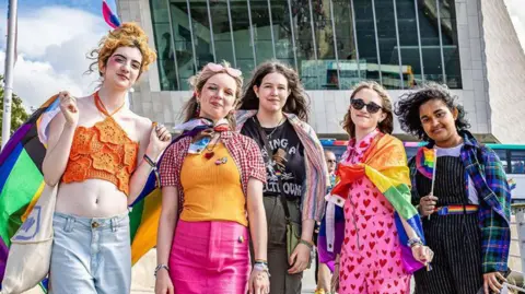 People wearing bright clothes and enjoying Liverpool in Pride on Liverpool Waterfront.