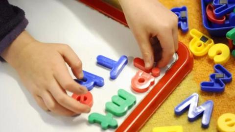 Child using magnetic letters on a whiteboard