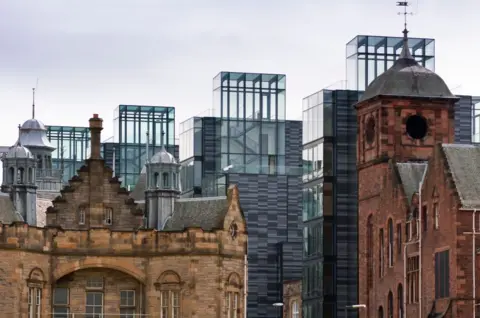 Getty Images A skyline view of older sandstone buildings and newer glass and cladding buildings in the centre of Edinburgh. 
