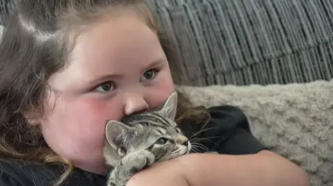 A young girl cuddling a kitten