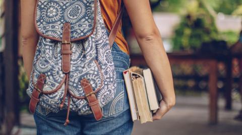 A woman with a backpack holding some books