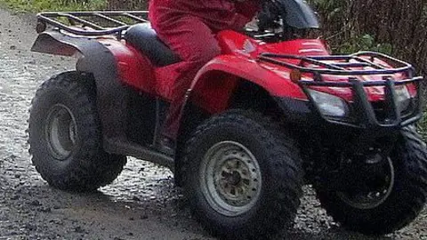 Red quadbike being ridden by a person wearing red overalls