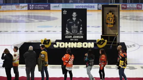 Reuters Fans walk past a memorial of Adam Johnson on the ice in Nottingham