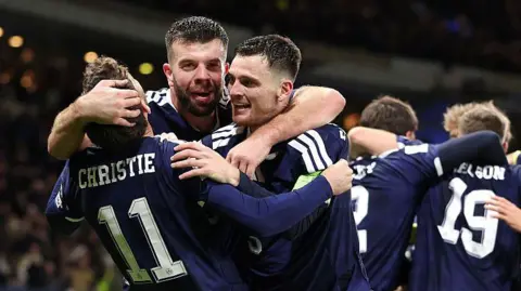 Scotland players celebrate with Grant Handley in the middle