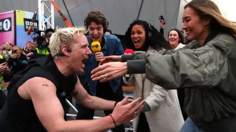 Getty Images Jamie Laing hugging his wife Sophie Habboo. Laing is wearing a black tank top and is emotional as he shouts with joy