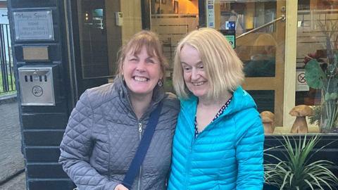 Mandy Redvers-Rowe and Gill Wake standing outside a restaurant with arms round each other smiling