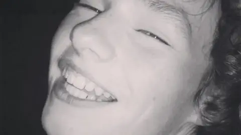 A black and white photo of a smiling Gabriel Santer, who has curly hair.