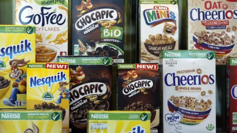 Boxes of Nestle breakfast products, including its Nesquik, Chocapic and Cheerios cereals, sit on three rows of a display.