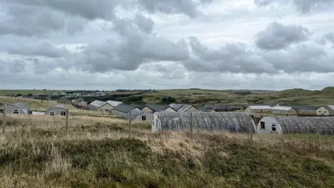 A picture showing a number of disused concrete huts on the former Penhale   military camp