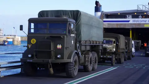 Brittany Ferries A row of large military trucks driving off the ship. At the front is a green military troop carrier.