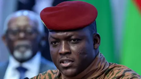 Ibrahim Traoré is pictured close up in beige military fatigues and red beret.