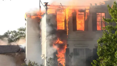 A white building with fire emerging from inside 