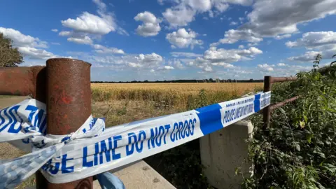 Stuart Woodward/BBC Blue and white police tape cordoning off a field.