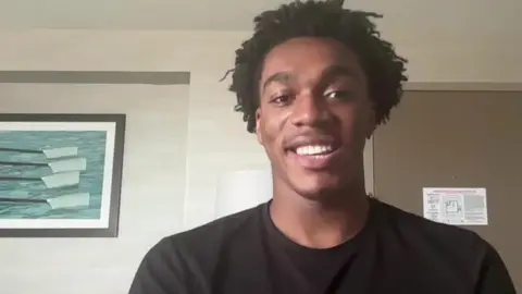 A screen shot of a zoom call with Amari Williams. He had short dark hair and is wearing a dark shirt.