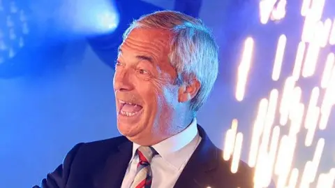 Celebrating onstage, Nigel Farage smiles as sparks fly from pyrotechnics on his left
