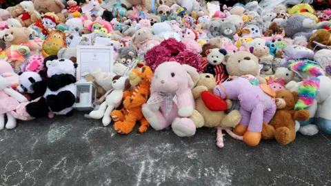 Reuters A huge pile of different cuddly toys on the pavement in Southport