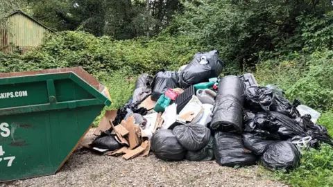 A mound of fly-tipped black bags and other items, including cannabis farm waste. 