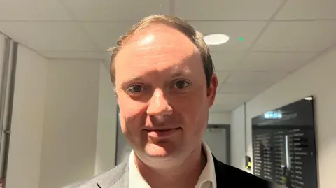 BBC A head-and-shoulders image of a man in a jacket and tie